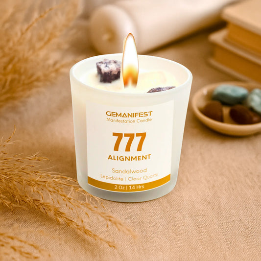 Gemanifest 777 Alignment candle on a textured surface with sandalwood and clear quartz stones.