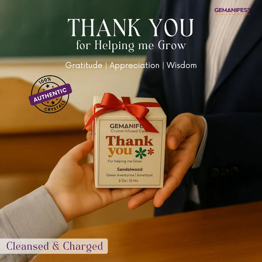 Person holding a 'Thank you Candle' box with a red ribbon, set against a blurred classroom background.