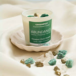 Abundance Manifestation Candle with Pyrite and Green Aventurine Crystals for Wealth and Prosperity.