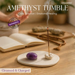Amethyst tumble stone on a ceramic dish with incense and books in the background, featuring GEMANIFEST branding.