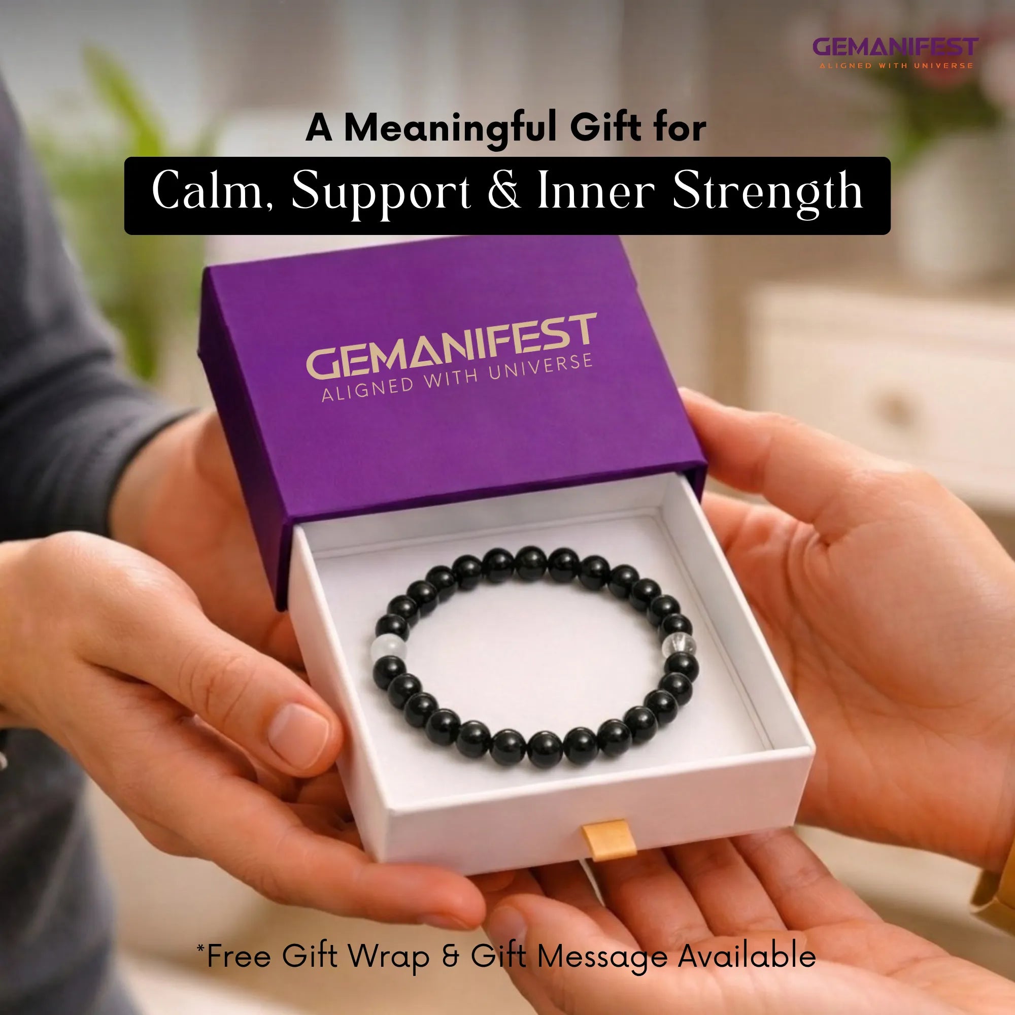 Black beaded bracelet in a 'GEMANIFEST' box held by hands with blurred background