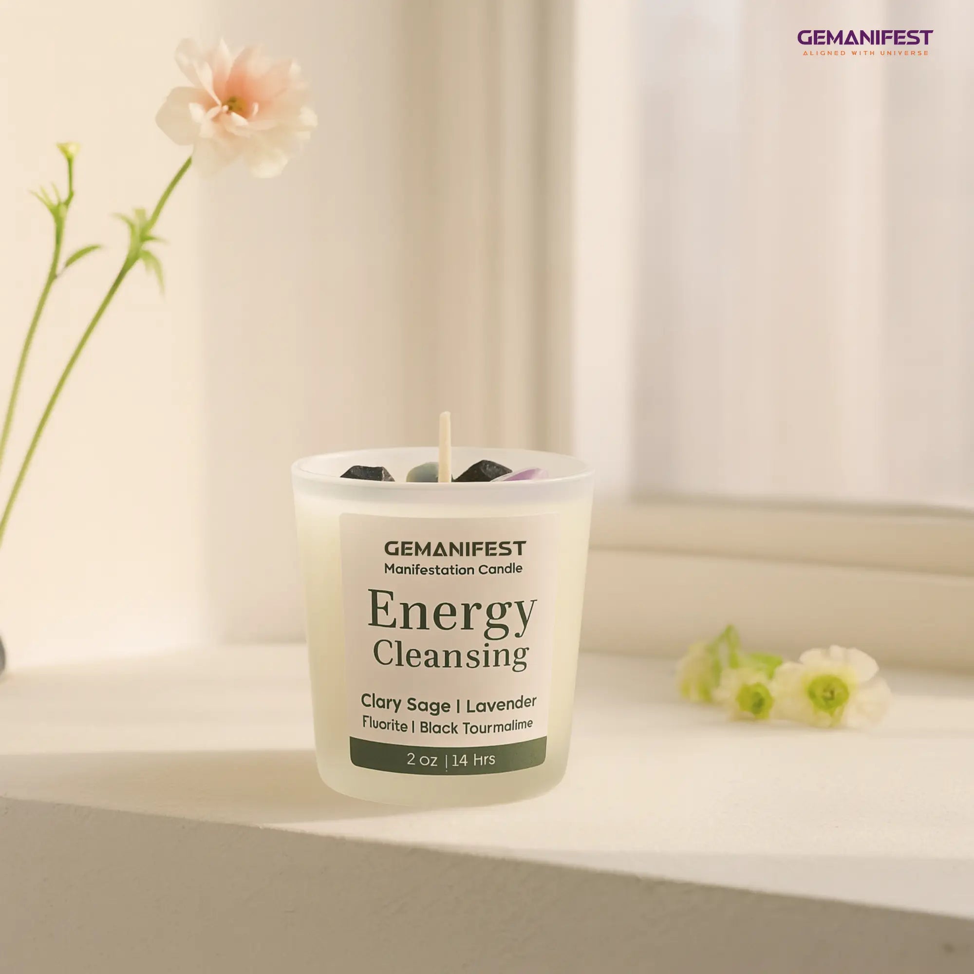 GEMANIFEST Energy Cleansing candle on a surface with flowers in the background