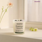 GEMANIFEST Energy Cleansing candle on a surface with flowers in the background