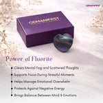 Heart-shaped fluorite crystal and purple packaging with Gemanifest branding on a light background.