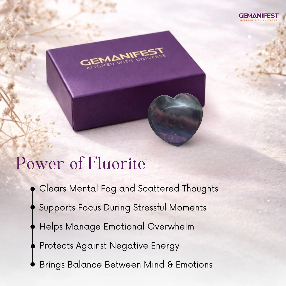 Heart-shaped fluorite crystal and purple packaging with Gemanifest branding on a light background.