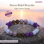 Stress relief bracelet with colored beads on a rock with a sunset background, featuring the brand 'GEMANIFEST'.