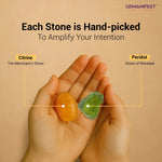 Hand holding two stones used in the candle, Citrine and Periodot, with text about hand-picked stones by GEMANIFEST.