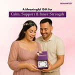 Man presenting a purple gift box to a woman with 'GEMANIFEST' branding on a pink background.