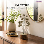Decorative pyrite tree on a wooden surface with a vase and mirror in the background.